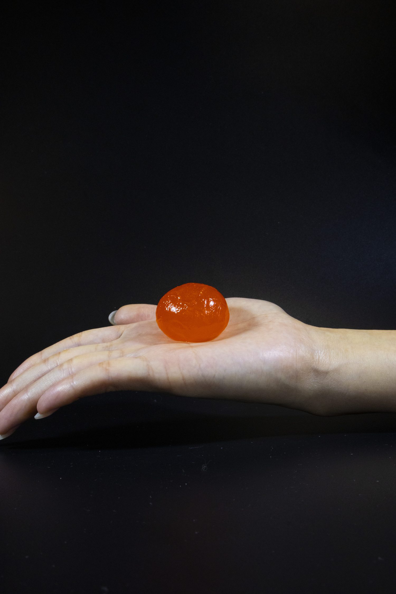 A single glistening salted duck egg yolk held in an open palm