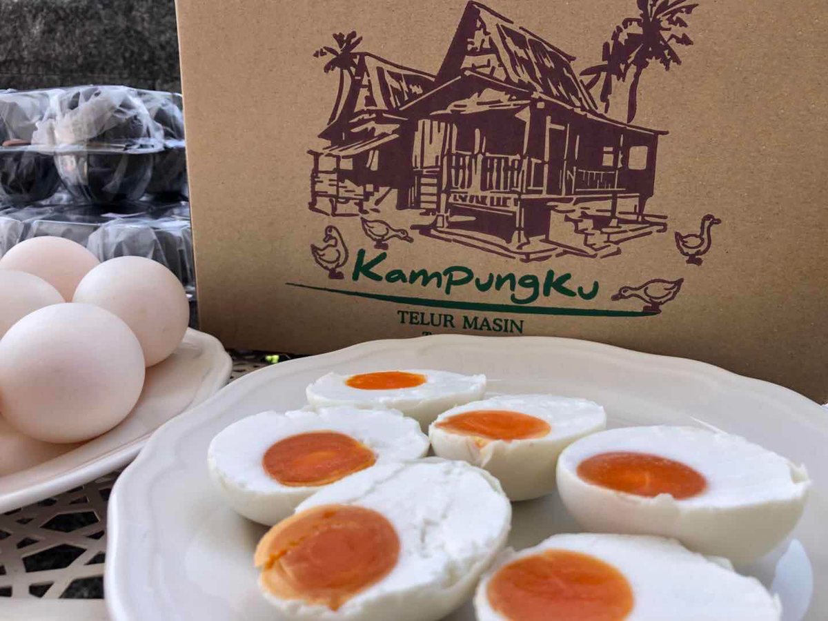 Kampungku Telur Masin salted duck eggs — whole eggs and halved salted eggs with bright orange yolks beside the heritage Kampungku box